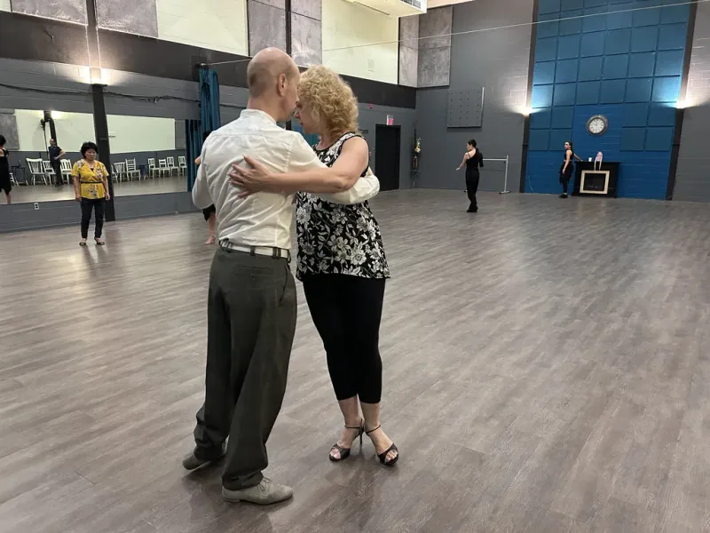 Couple in close embrace on the studio floor during beginner Argentine tango dance classes in Ottawa at DQ Ballroom & Fitness