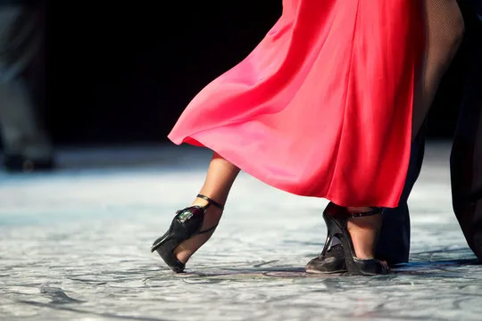Close view of a dancer's footwork beneath a swirling red skirt, the focus of Argentine tango dance classes in Ottawa