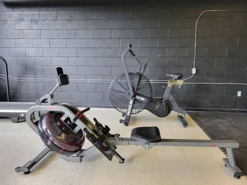 Rowing machine and air bike against a brick wall in the Ottawa fitness center at DQ Ballroom & Fitness