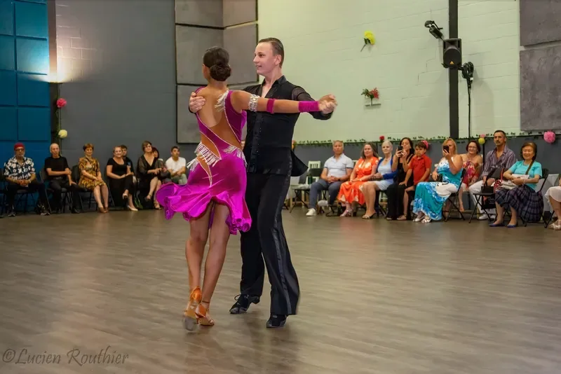 Couple in a magenta dress and black outfit dancing before an audience at intermediate jive dance classes in Ottawa