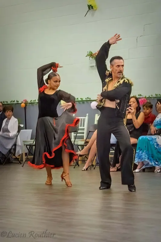Couple performing a sharp paso doble line in front of a seated audience at a beginner paso doble dance class in Ottawa
