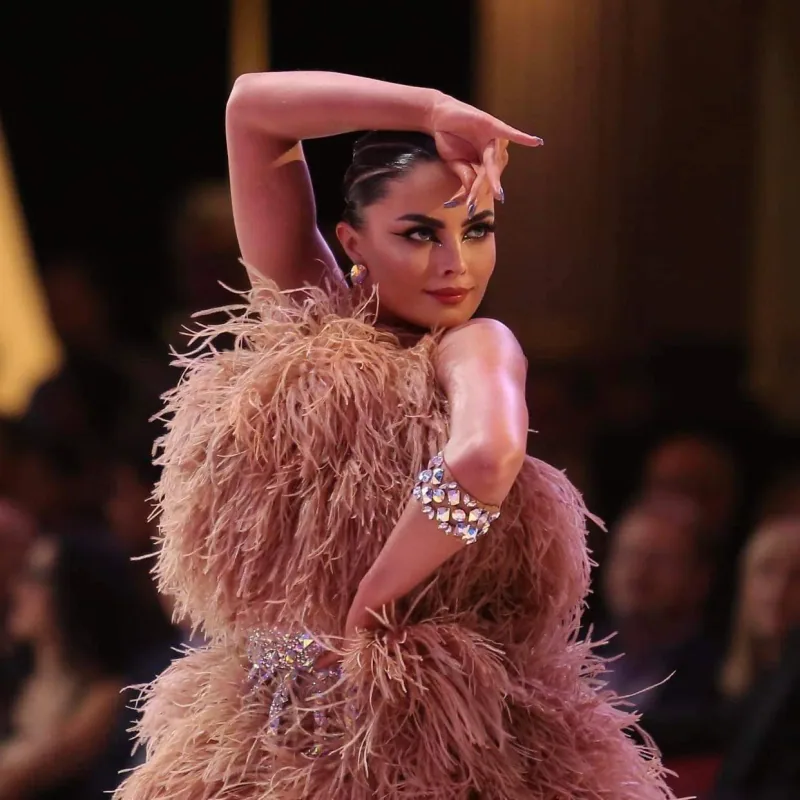 Latin dancer in a feathered costume holding a dramatic pose, the kind of styling taught in Ottawa paso doble dance classes