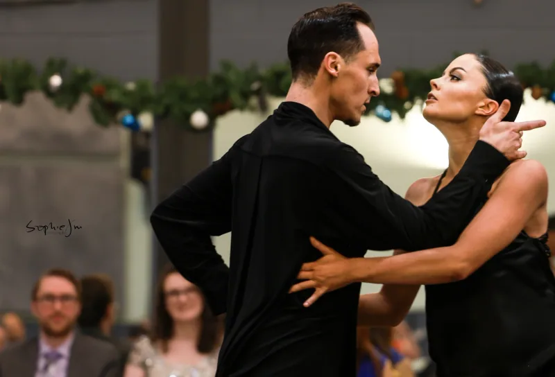 Couple in black holding a close face-to-face pose during a rumba dance performance at DQ Ballroom & Fitness in Ottawa