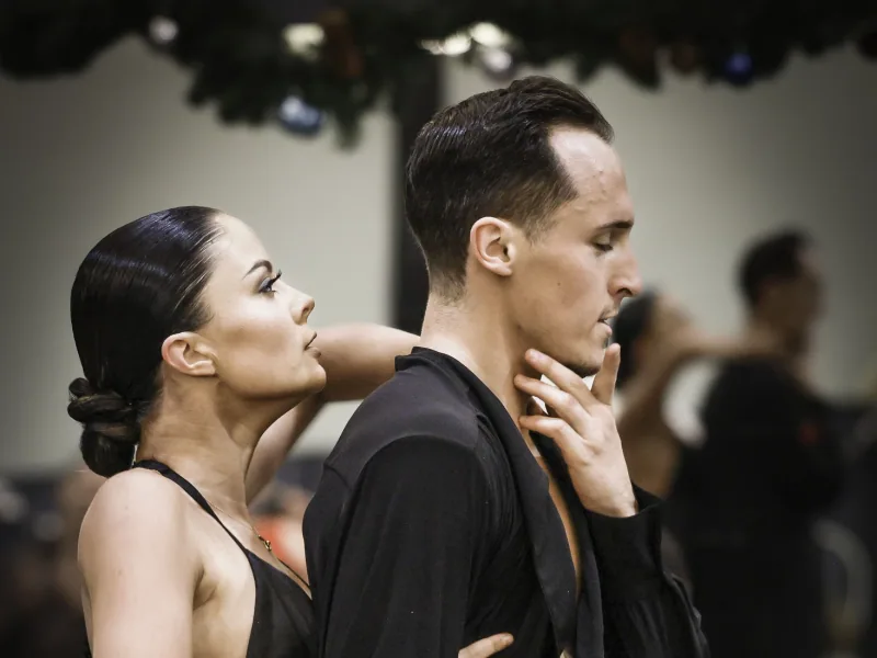 Close shot of a couple in black holding a poised Latin frame in an intermediate rumba dance class in Ottawa
