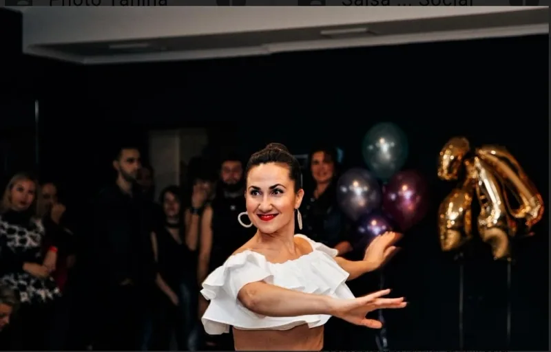 Woman in a white ruffled top dancing before onlookers at a social, reflecting salsa rueda dance classes in Ottawa at DQ Ballroom & Fitness