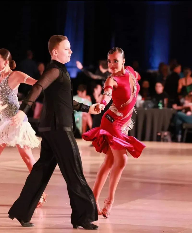 Couple performing a samba routine in costume on the competition floor, taught in samba dance classes in Ottawa at DQ Ballroom & Fitness