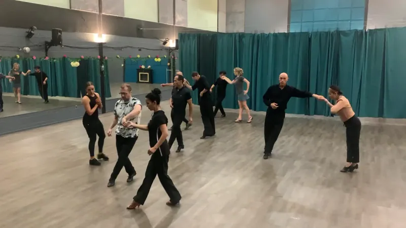 Group of dancers in dark attire working through steps in an intermediate samba dance class in Ottawa at DQ Ballroom & Fitness